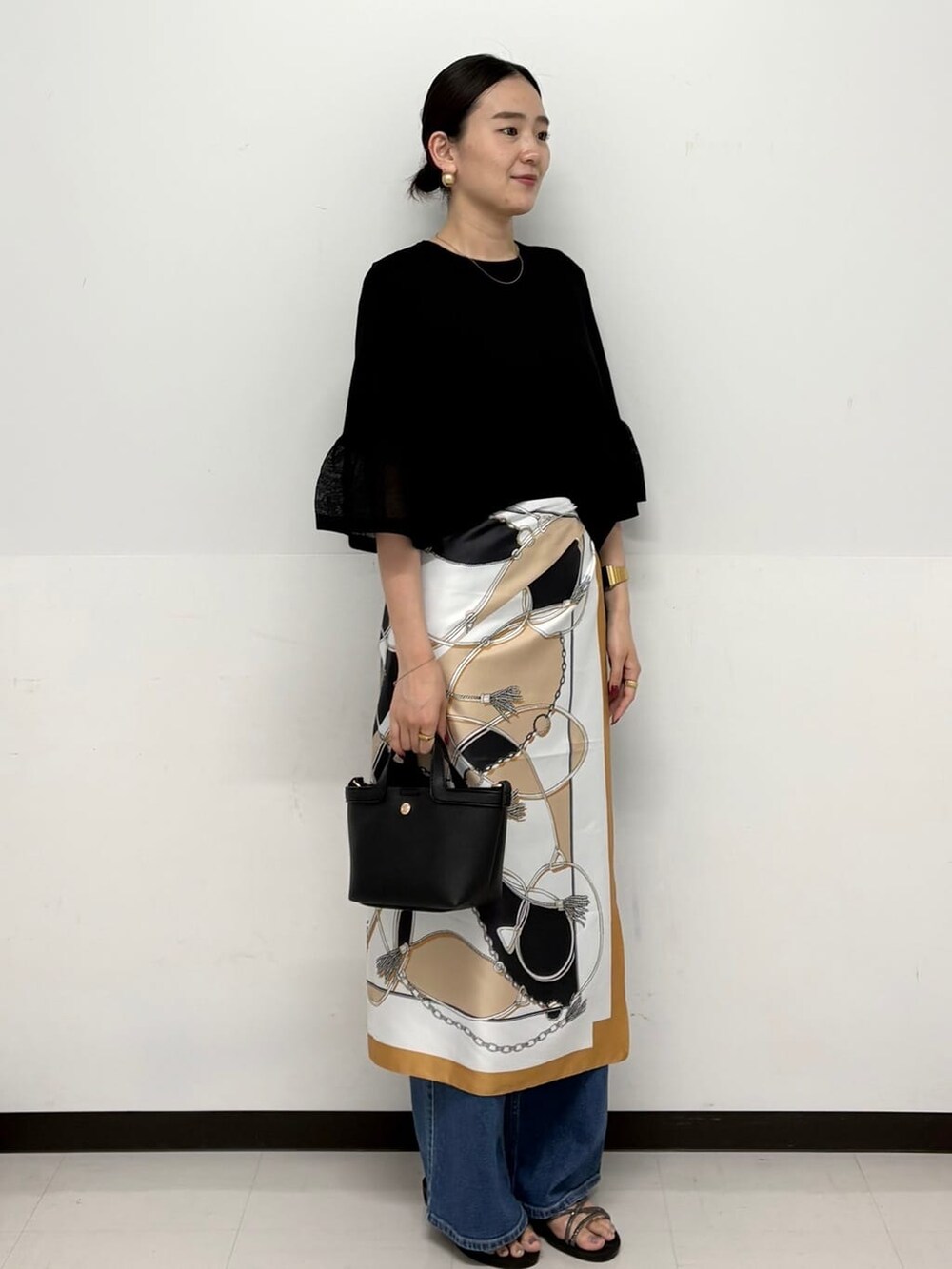 ブルー系のデニムパンツ、ブラック系のショルダーバッグ、シルバー系のサンダルを着用したレディースの春コーディネートの2枚目の写真