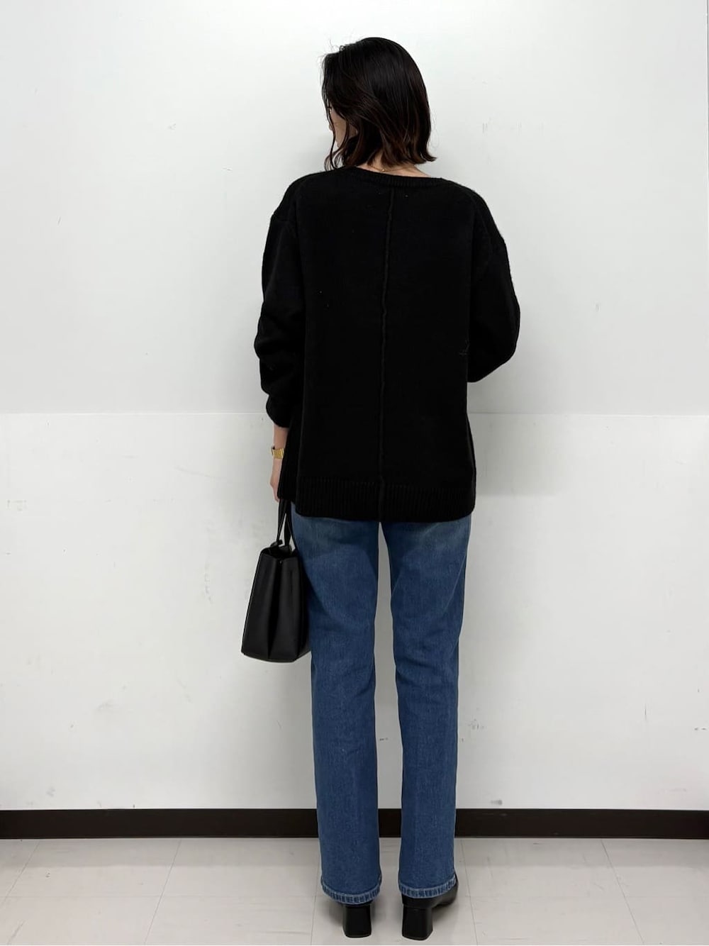 ブラック系のニット/セーター、ブルー系のデニムパンツ、ブラック系のトートバッグを着用したレディースの冬コーディネートの4枚目の写真