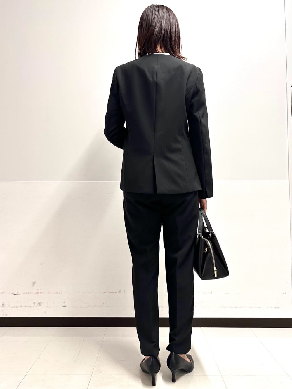 ブラック系のノーカラージャケット、ブラック系のその他パンツ、ブラック系のパンプスを着用したレディースの冬コーディネートの4枚目の写真