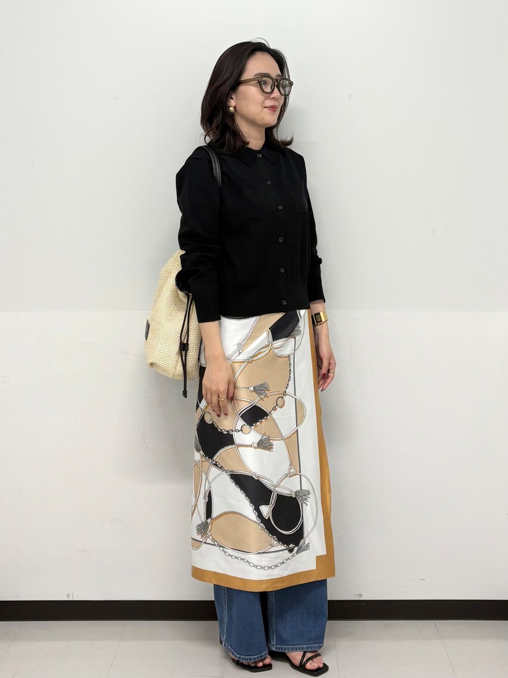 ブルー系のデニムパンツ、ブラック系のサンダル、ブラック系のカーディガン/ボレロを着用したレディースの春コーディネートの2枚目の写真