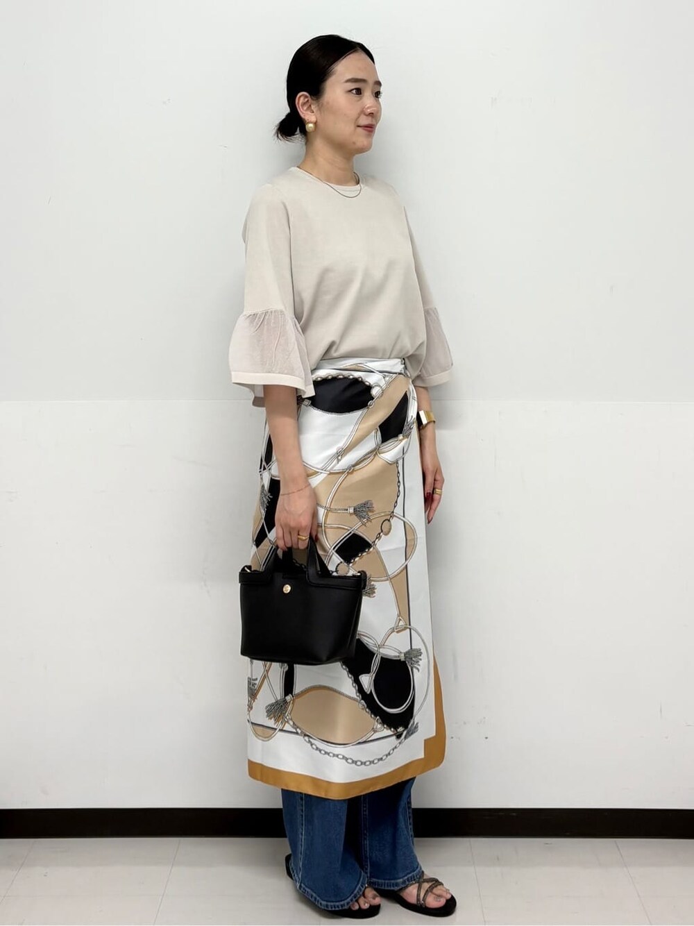 ブルー系のデニムパンツ、ブラック系のショルダーバッグ、シルバー系のサンダルを着用したレディースの春コーディネートの2枚目の写真