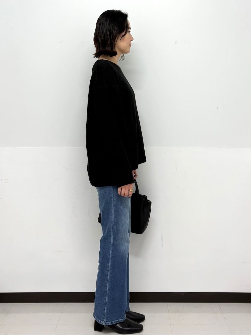 ブラック系のニット/セーター、ブルー系のデニムパンツ、ブラック系のトートバッグを着用したレディースの冬コーディネートの3枚目の写真