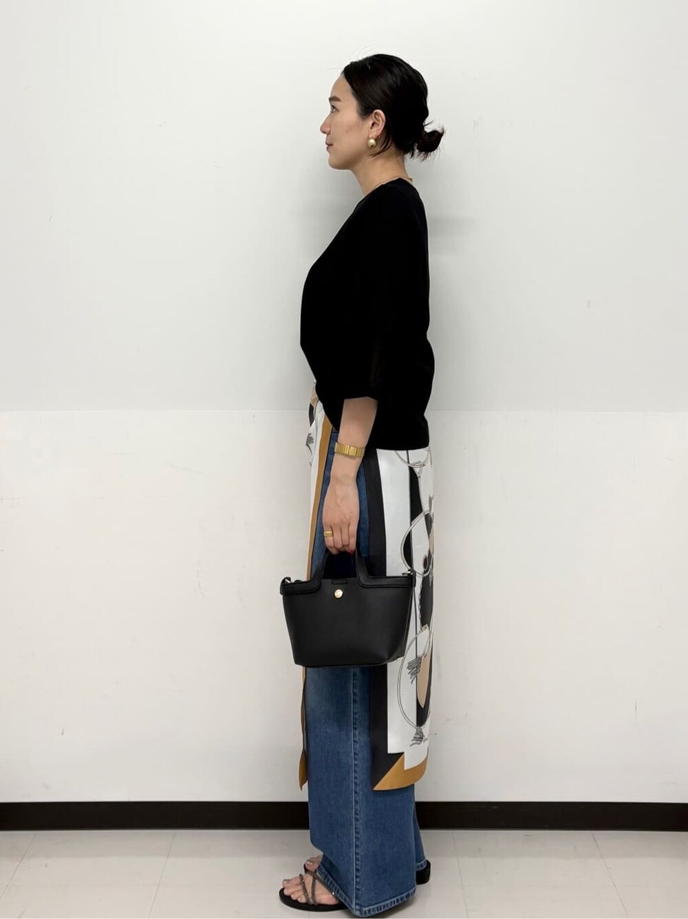 ブルー系のデニムパンツ、ブラック系のショルダーバッグ、シルバー系のサンダルを着用したレディースの春コーディネートの4枚目の写真