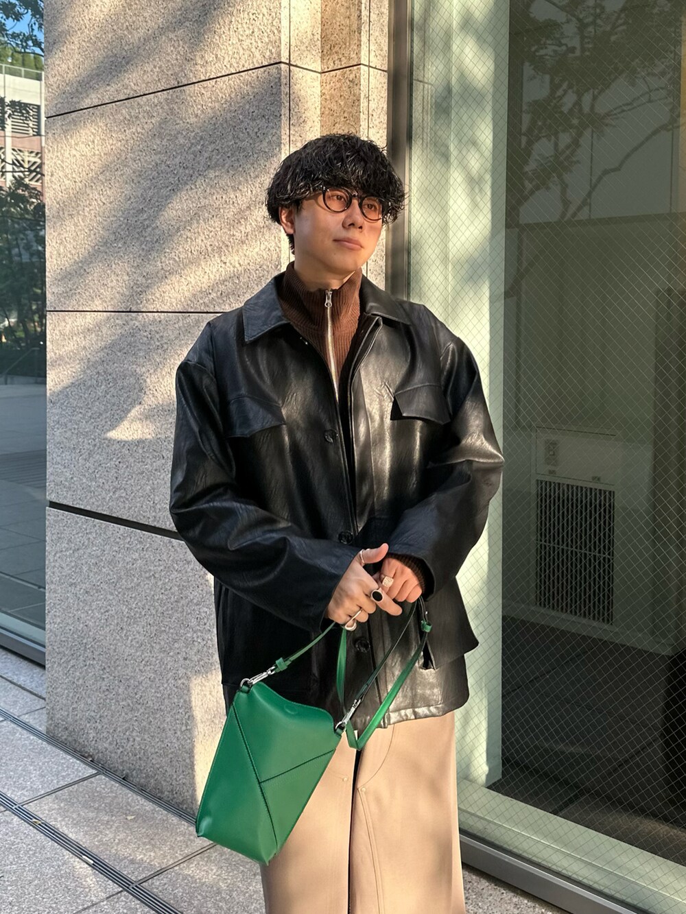 ブラック系のミリタリージャケット、ブラウン系のブルゾン、ベージュ系のスラックスを着用したメンズの秋コーディネートの4枚目の写真