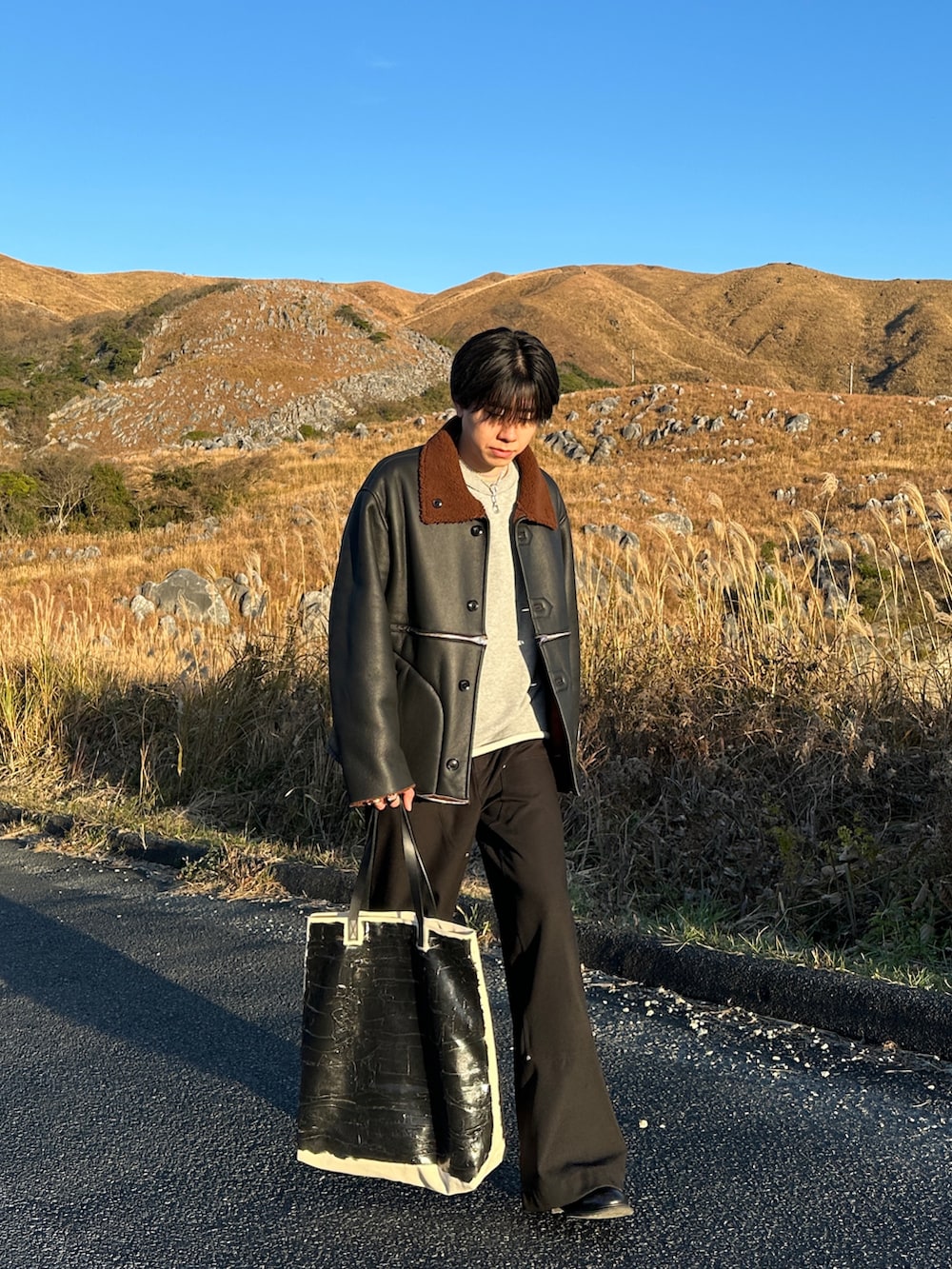 グレー系のスウェット、ブラック系のスラックス、ブラック系のブーツを着用したメンズの冬コーディネートの2枚目の写真