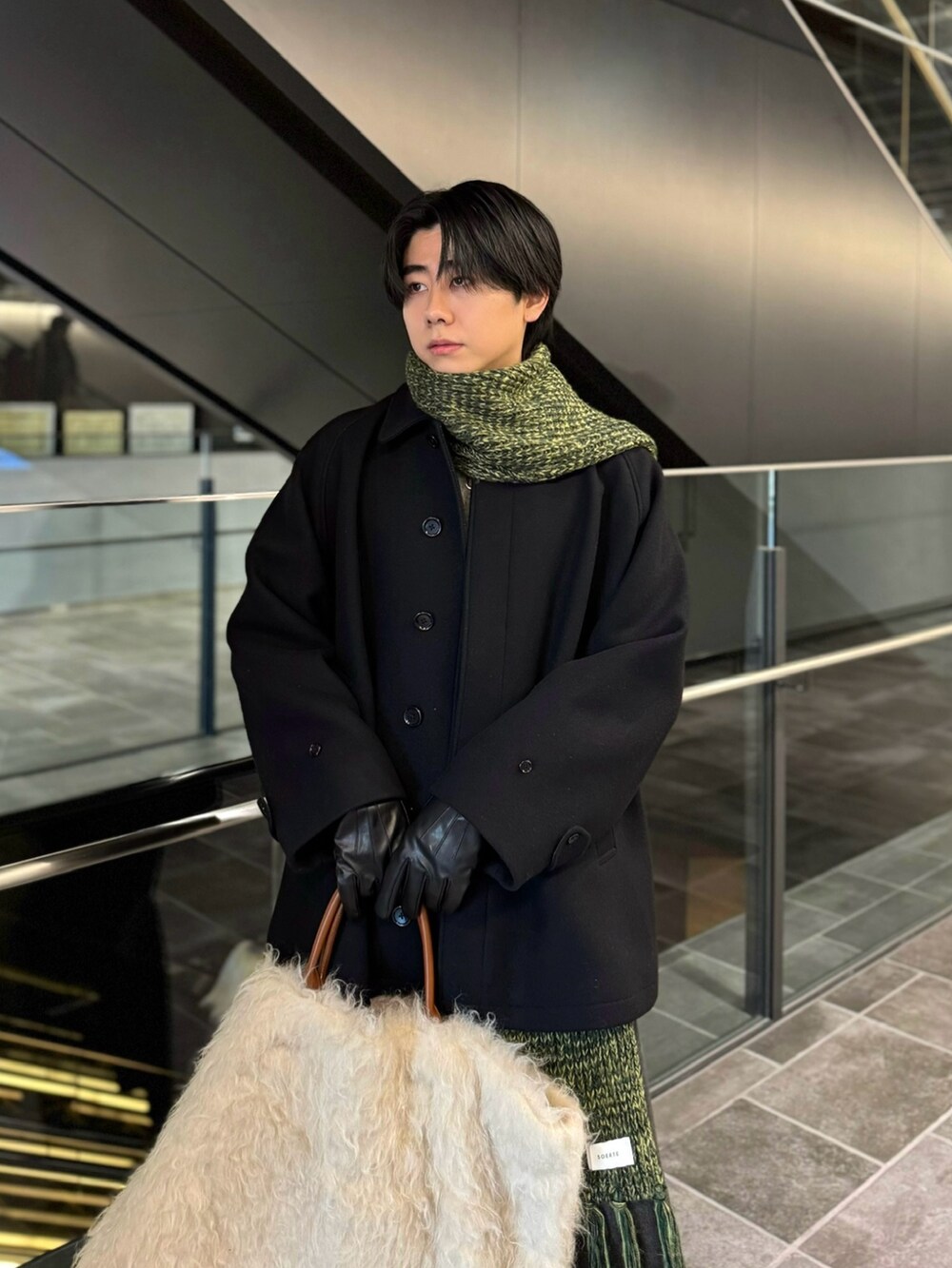 ブラック系のステンカラーコート、ブラック系のデニムパンツ、ブラック系のブーツを着用したメンズの冬コーディネートの4枚目の写真