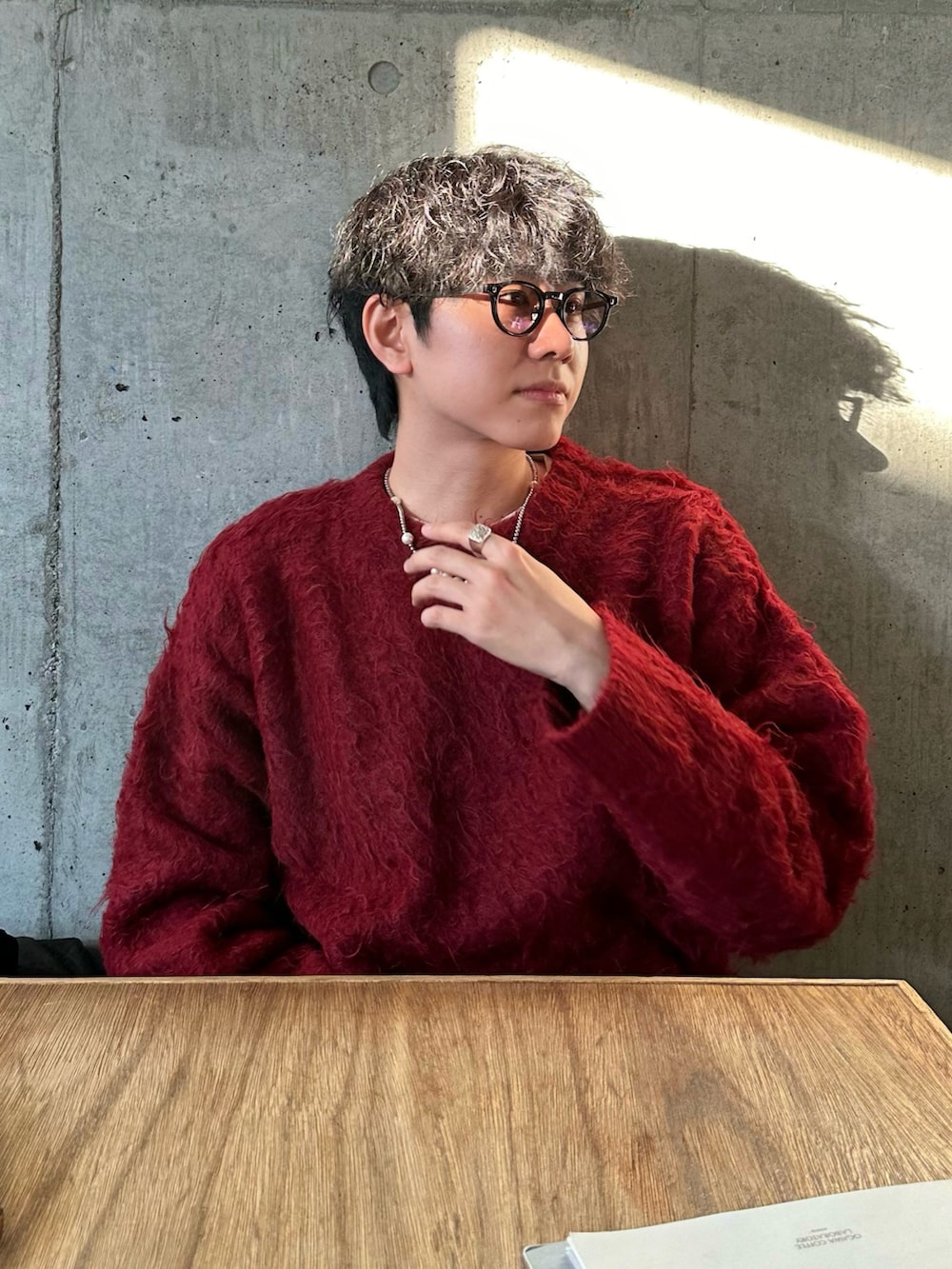 レッド系のニット/セーター、グレー系のデニムパンツを着用したメンズの秋コーディネートの2枚目の写真