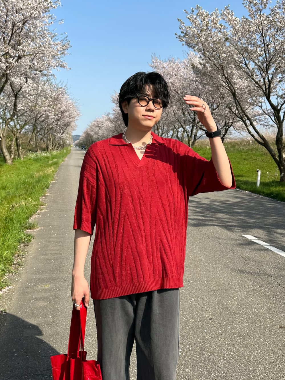 レッド系のポロシャツ、グレー系のデニムパンツ、レッド系のトートバッグを着用したメンズの夏コーディネートの3枚目の写真
