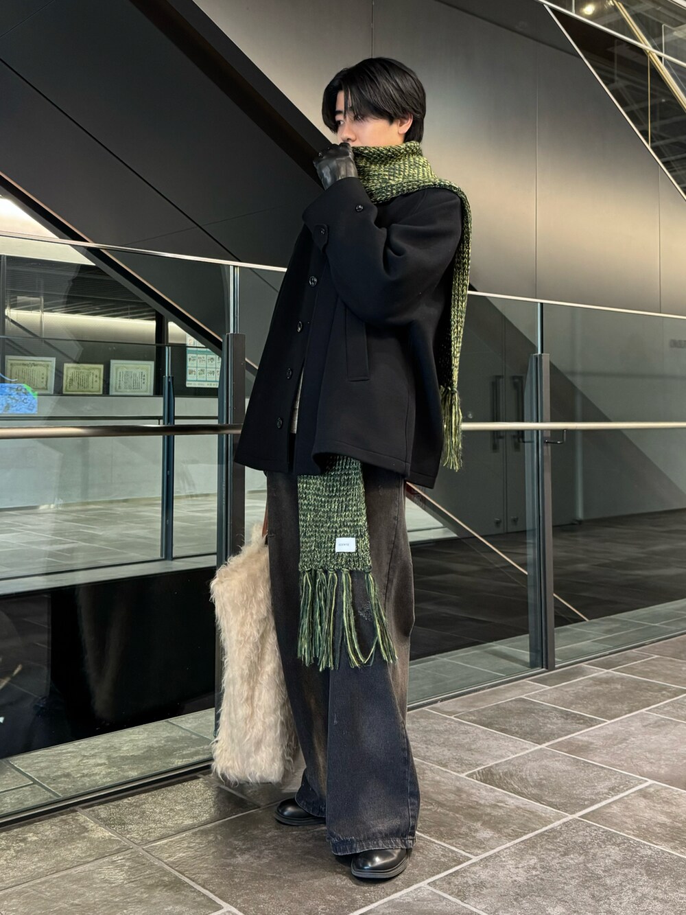 ブラック系のステンカラーコート、ブラック系のデニムパンツ、ブラック系のブーツを着用したメンズの冬コーディネートの2枚目の写真