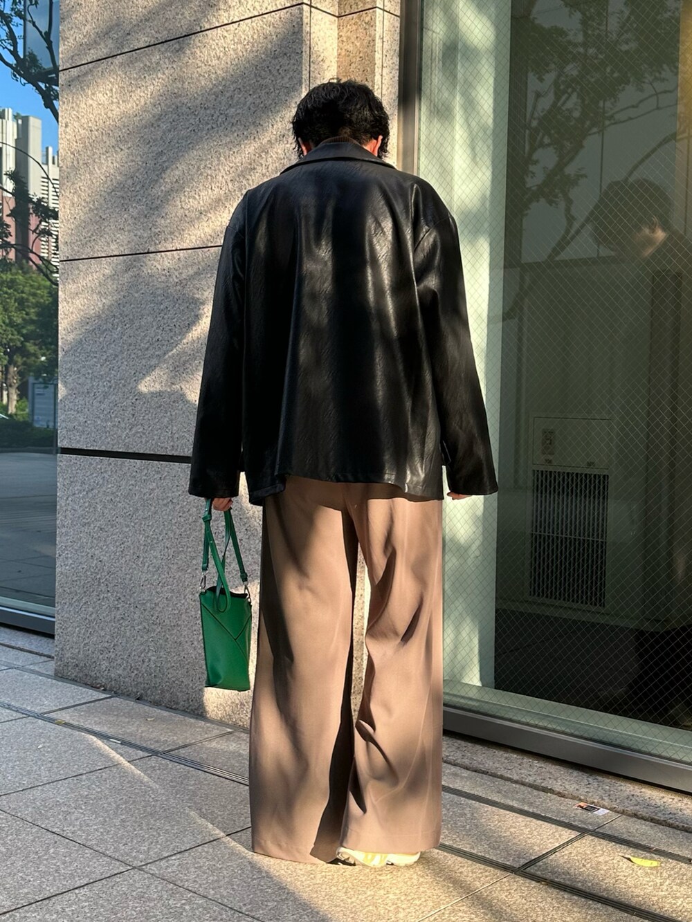 ブラック系のミリタリージャケット、ブラウン系のブルゾン、ベージュ系のスラックスを着用したメンズの秋コーディネートの3枚目の写真