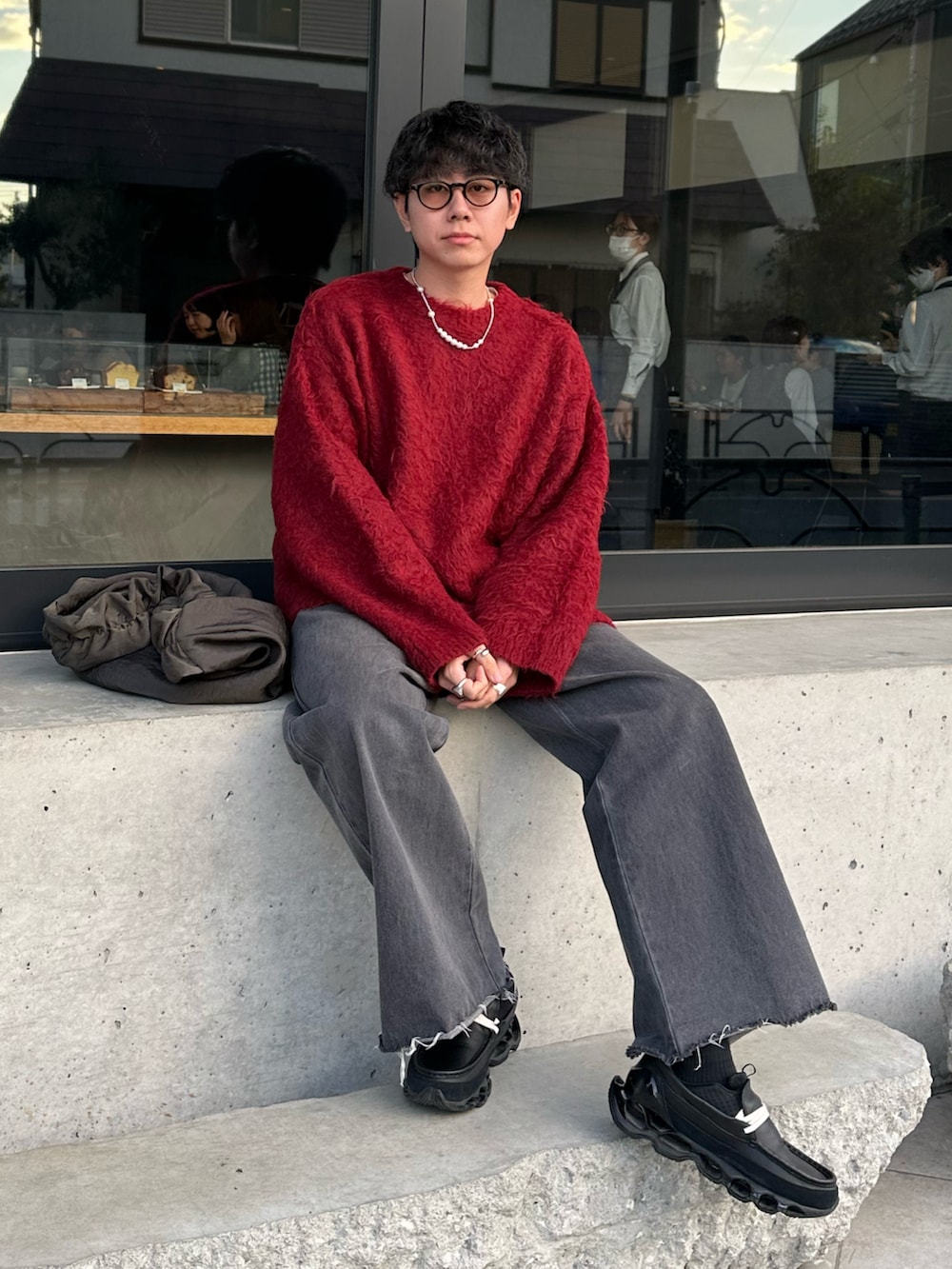 レッド系のニット/セーター、グレー系のデニムパンツを着用したメンズの秋コーディネートの4枚目の写真