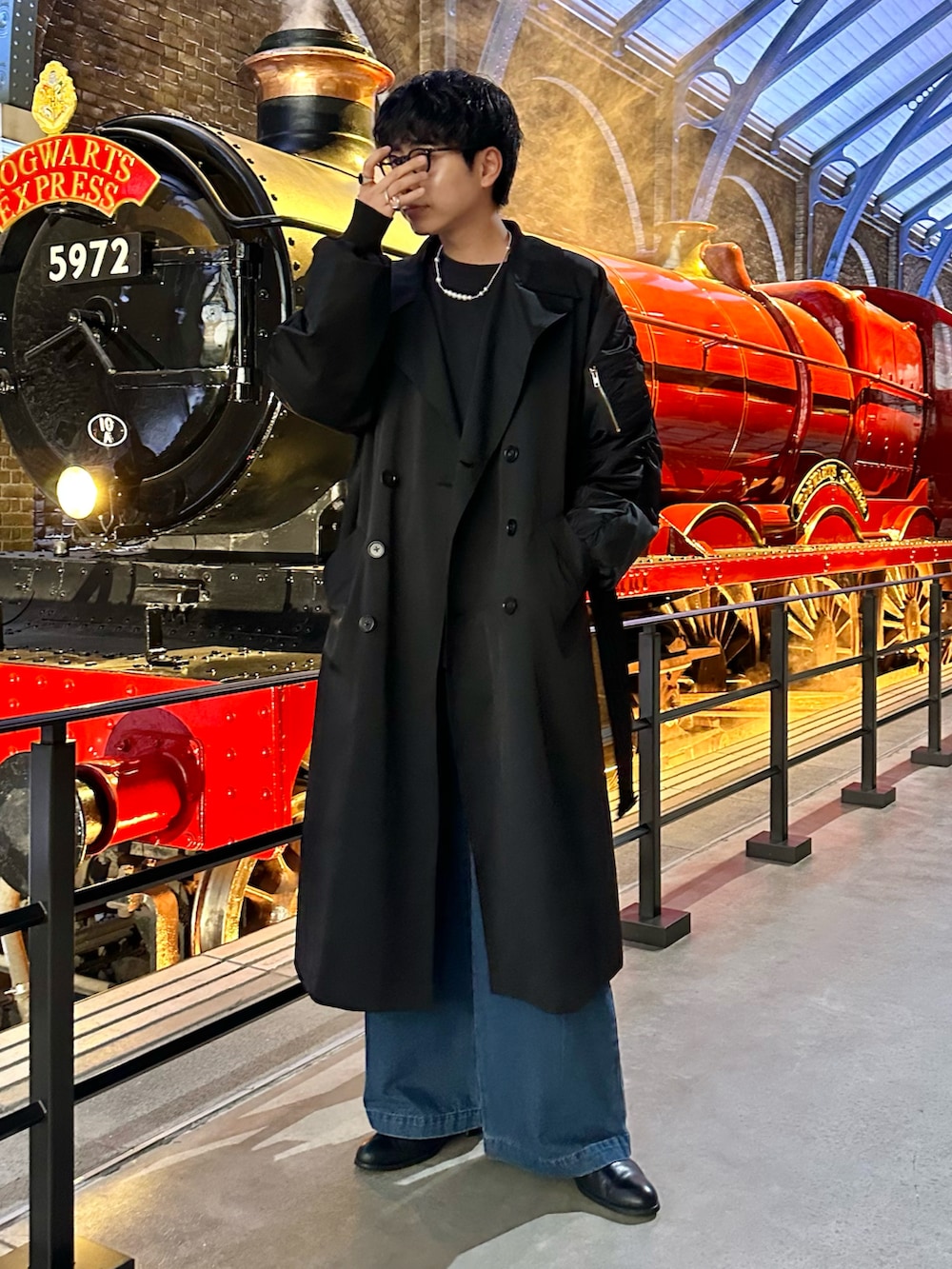 ブラック系のトレンチコート、ブルー系のデニムパンツを着用したメンズの秋コーディネートの2枚目の写真