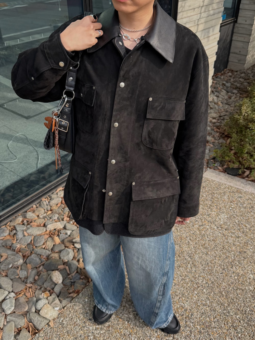 ブラック系のハンドバッグ、ブラック系のカバーオール、ブルー系のデニムパンツを着用したメンズの春コーディネートの3枚目の写真