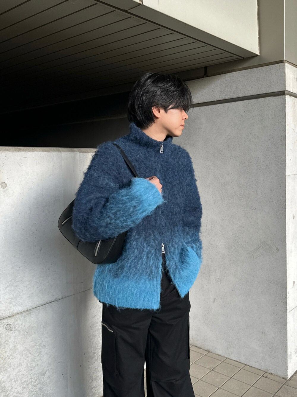 ブルー系のニット/セーター、ブラック系のカーゴパンツ、ブラック系のブーツを着用したメンズの冬コーディネートの3枚目の写真