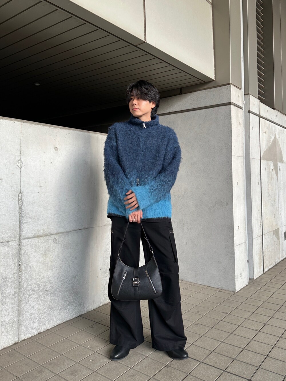 ブルー系のニット/セーター、ブラック系のカーゴパンツ、ブラック系のブーツを着用したメンズの冬コーディネートの2枚目の写真