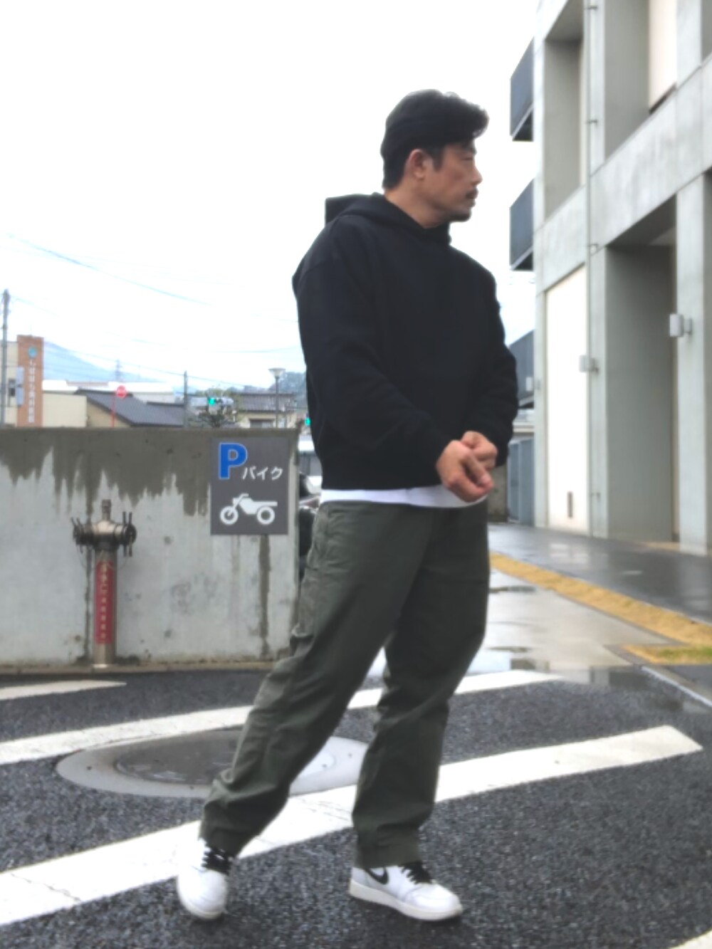 ブラック系のパーカー、グリーン系のその他パンツ、ホワイト系のスニーカーを着用したメンズの春コーディネートの2枚目の写真