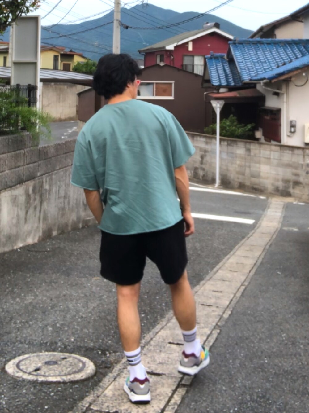 ブラック系のその他パンツ、その他のスニーカー、グリーン系のTシャツ/カットソーを着用したメンズの夏コーディネートの2枚目の写真