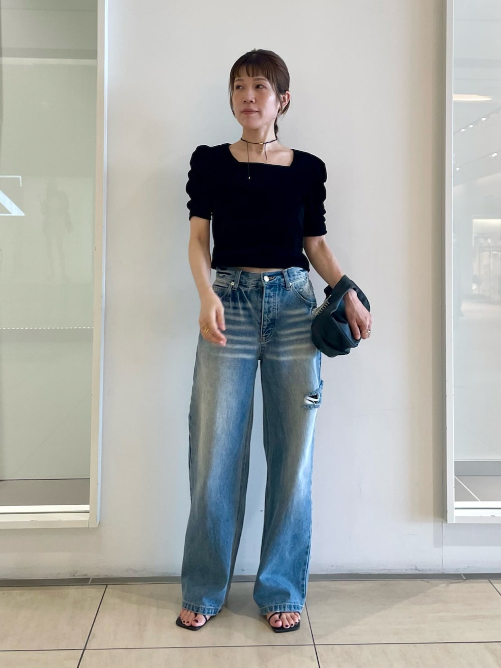ブラック系のTシャツ/カットソー、ブルー系のデニムパンツ、ブラック系のサンダルを着用したレディースの夏コーディネートの3枚目の写真