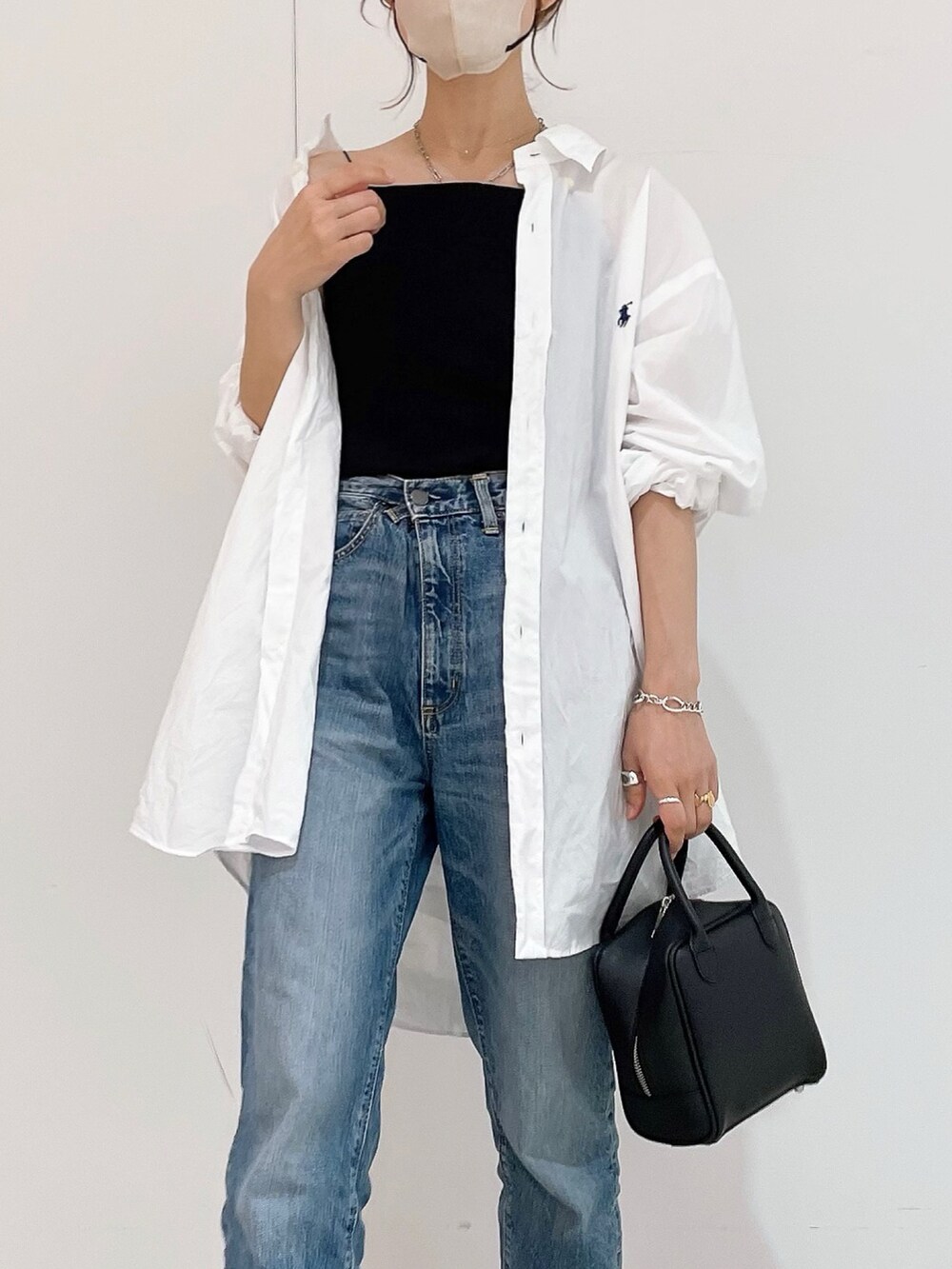 ブラック系のキャミソール、ホワイト系のシャツ/ブラウス、ブルー系のデニムパンツを着用したレディースの夏コーディネートの2枚目の写真