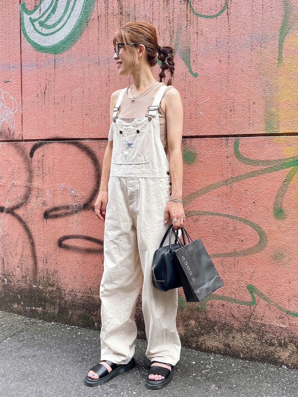 ベージュ系のタンクトップ、ホワイト系のサロペット/オーバーオール、ブラック系のサンダルを着用したレディースの夏コーディネートの2枚目の写真