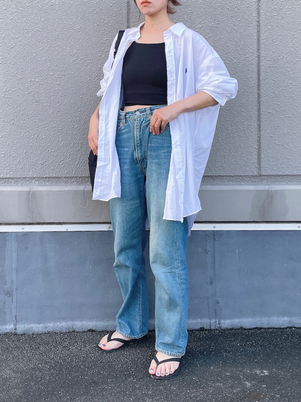 ホワイト系のシャツ/ブラウス、ブルー系のデニムパンツ、ブラック系のビーチサンダルを着用したレディースの夏コーディネートの3枚目の写真