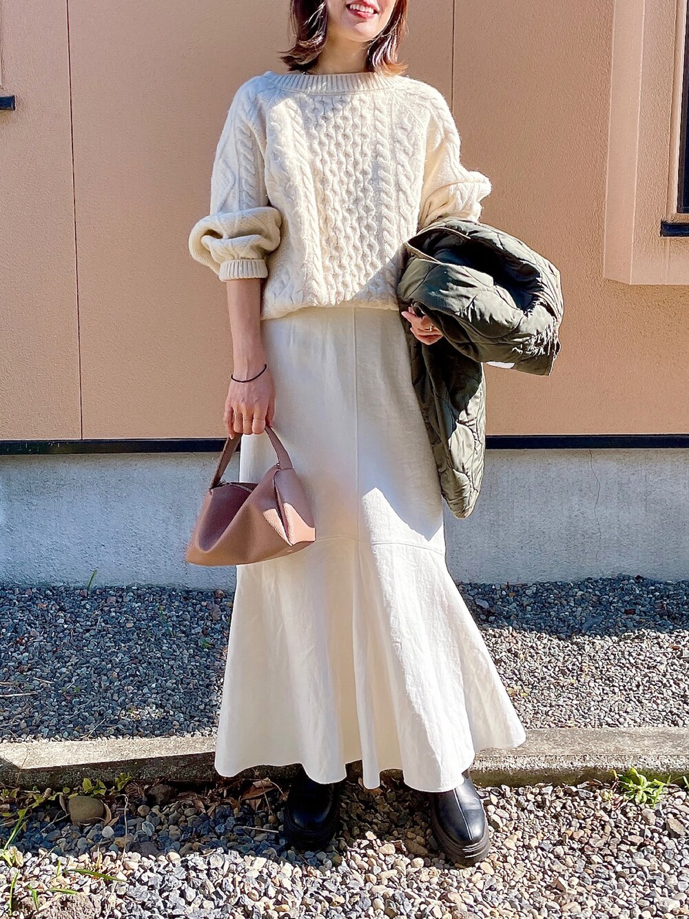 ブラック系のブーツ、ベージュ系のショルダーバッグ、グリーン系のリングを着用したレディースの冬コーディネートの2枚目の写真