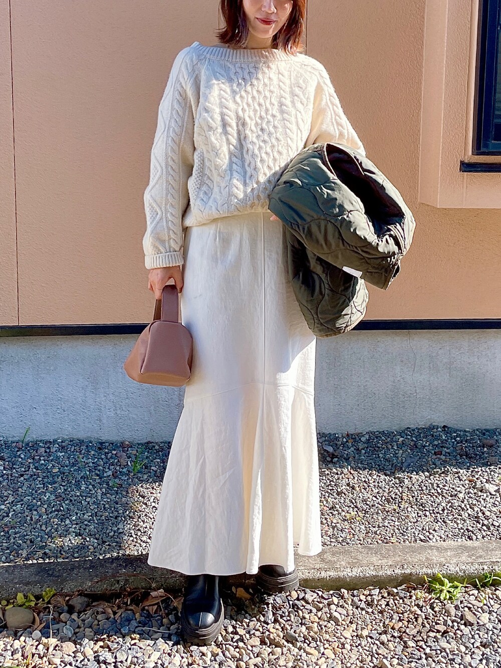 ブラック系のブーツ、ベージュ系のショルダーバッグ、グリーン系のリングを着用したレディースの冬コーディネートの3枚目の写真