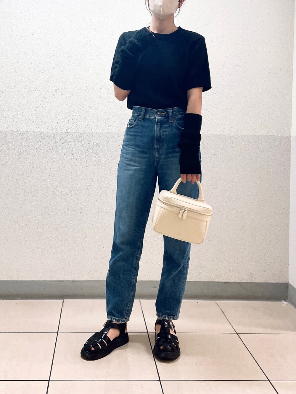 ブラック系のニット/セーター、ブルー系のデニムパンツ、ブラック系のサンダルを着用したレディースの夏コーディネートの4枚目の写真