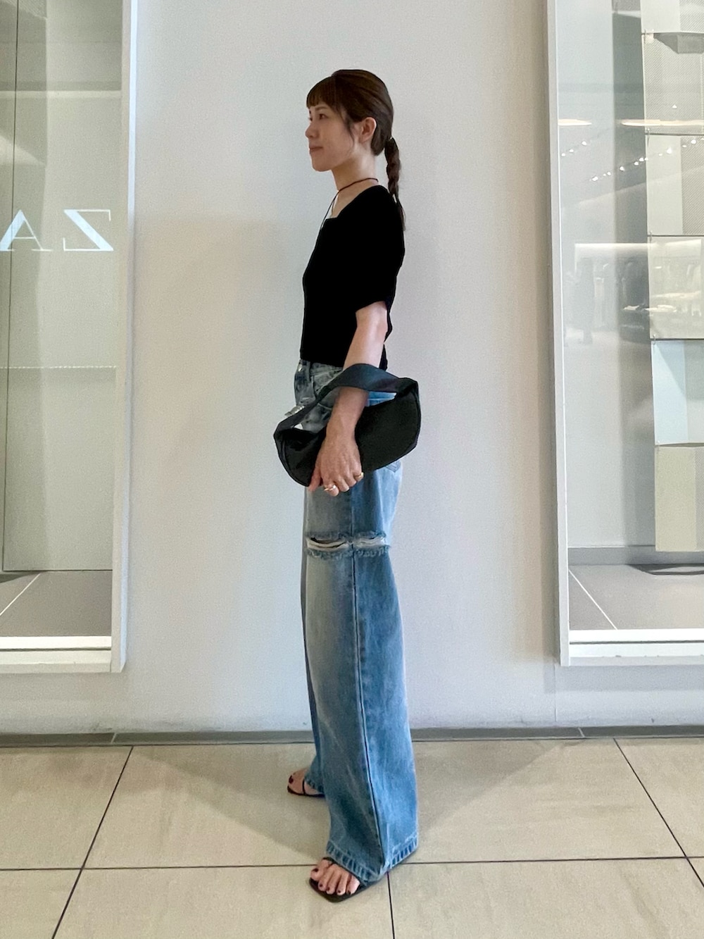 ブラック系のTシャツ/カットソー、ブルー系のデニムパンツ、ブラック系のサンダルを着用したレディースの夏コーディネートの4枚目の写真