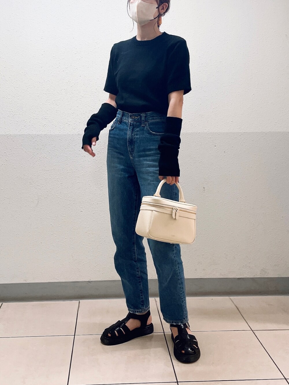 ブラック系のニット/セーター、ブルー系のデニムパンツ、ブラック系のサンダルを着用したレディースの夏コーディネートの3枚目の写真