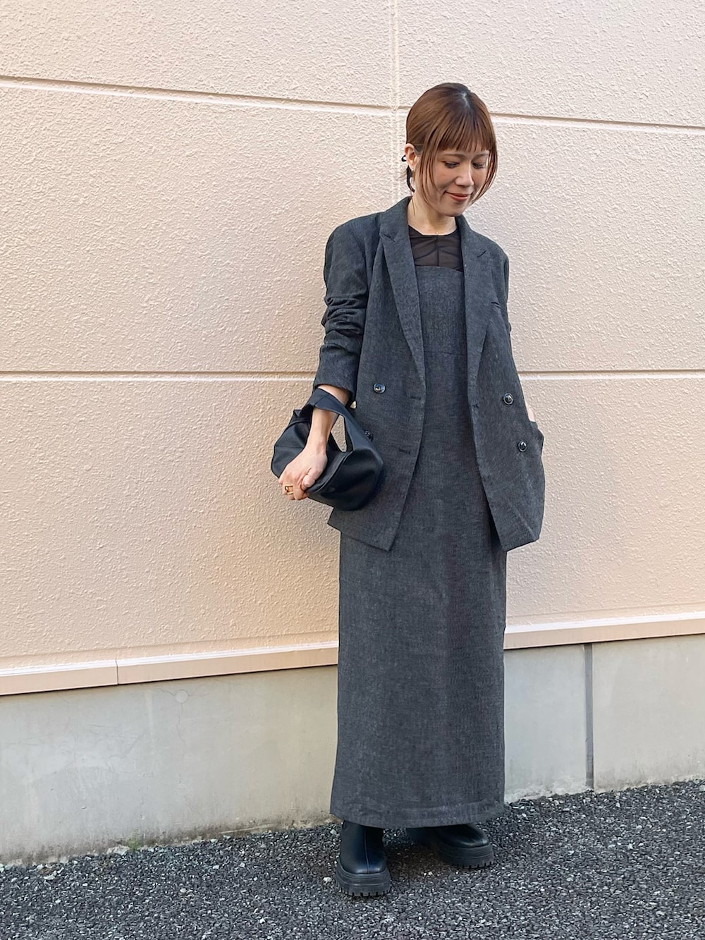 グレー系のテーラードジャケット、グレー系のワンピース、ブラック系のブーツを着用したレディースの春コーディネートの2枚目の写真