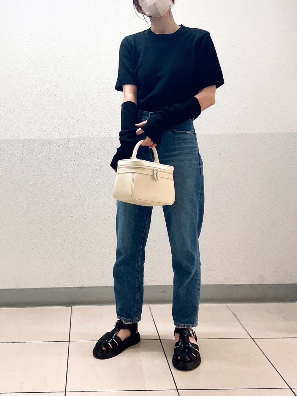 ブラック系のニット/セーター、ブルー系のデニムパンツ、ブラック系のサンダルを着用したレディースの夏コーディネートの2枚目の写真