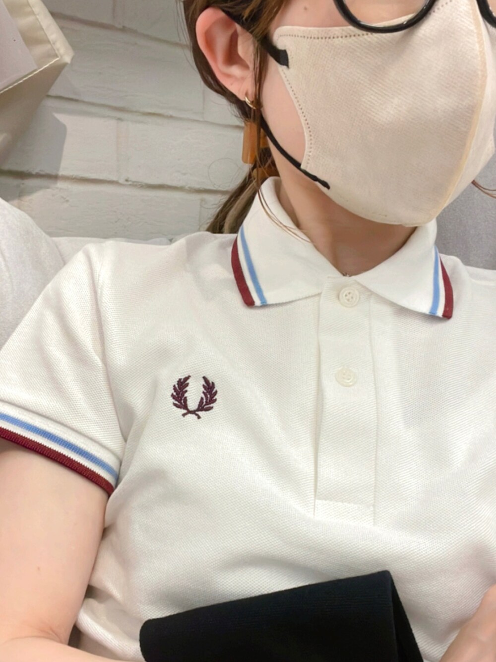 ホワイト系のポロシャツ、イエロー系のチノパンツ、ブラック系のサンダルを着用したレディースの夏コーディネートの2枚目の写真