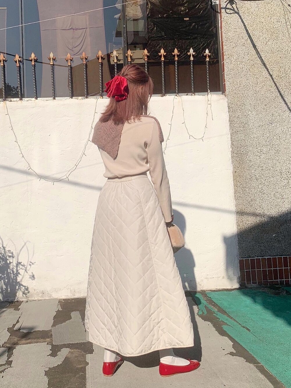 ホワイト系のニット/セーター、ホワイト系のスカートを着用したレディースの冬コーディネートの2枚目の写真