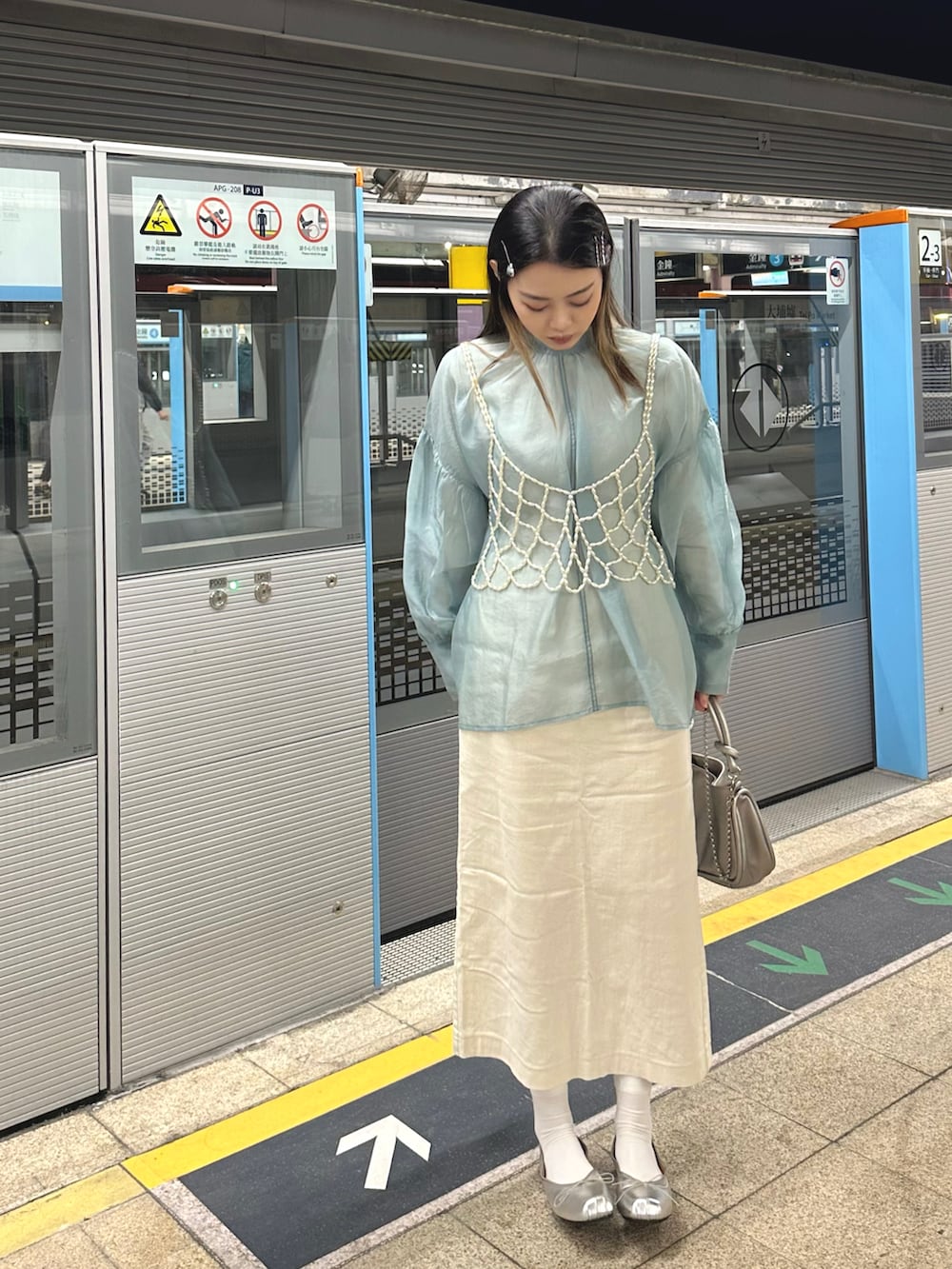 ホワイト系のベスト、ブルー系のシャツ/ブラウス、ベージュ系のスカートを着用したレディースの冬コーディネートの2枚目の写真