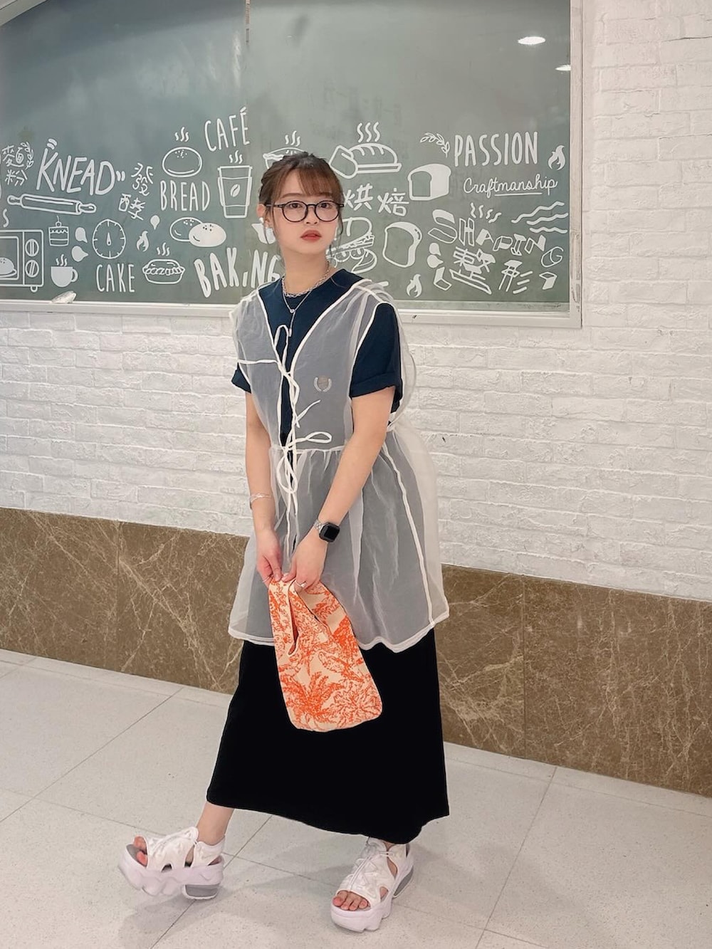 ホワイト系のベスト、ブルー系のTシャツ/カットソー、ホワイト系のサンダルを着用したレディースの春コーディネートの2枚目の写真