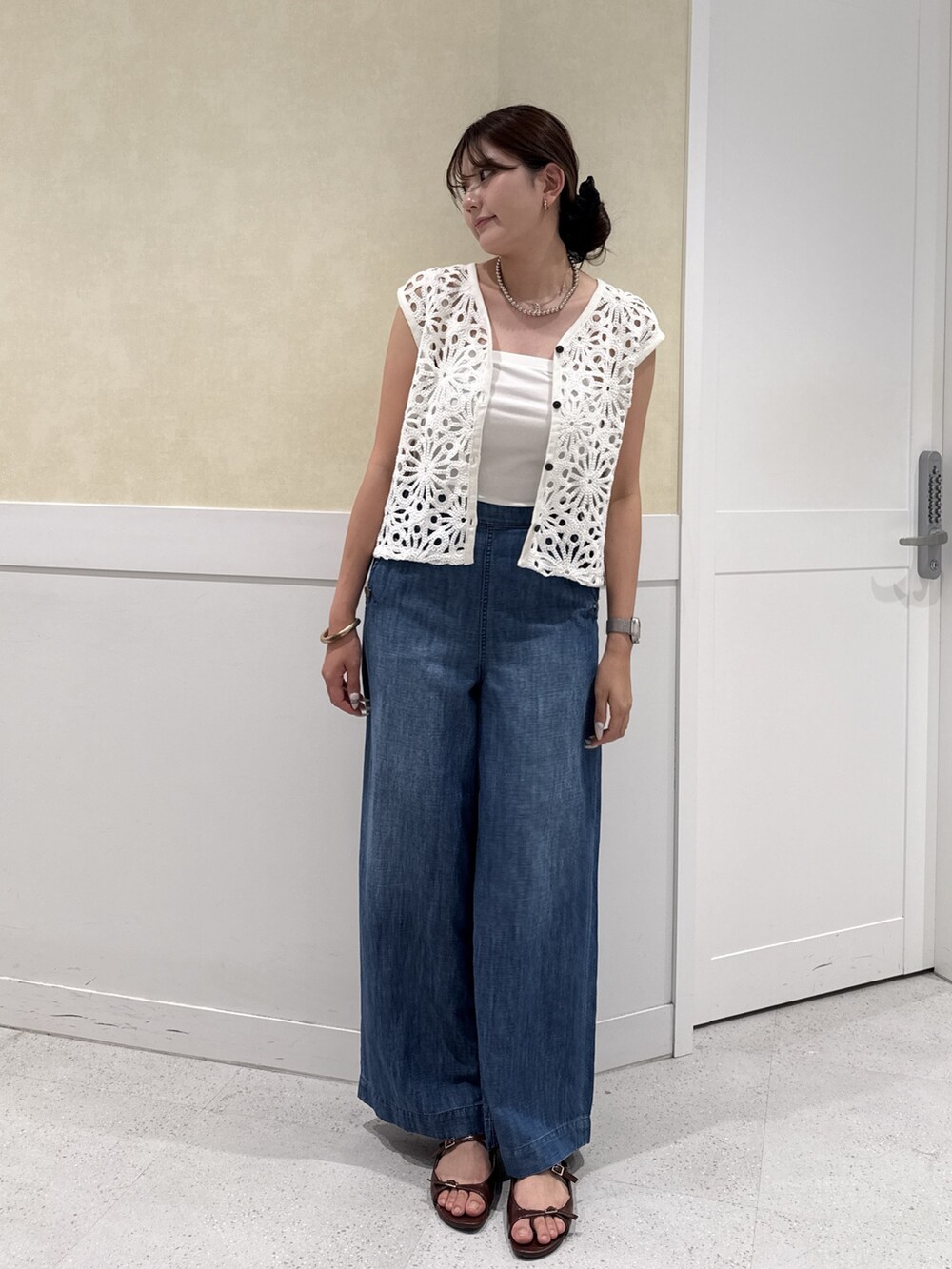 ホワイト系のベスト、ブルー系のデニムパンツを着用したレディースの夏コーディネートの5枚目の写真