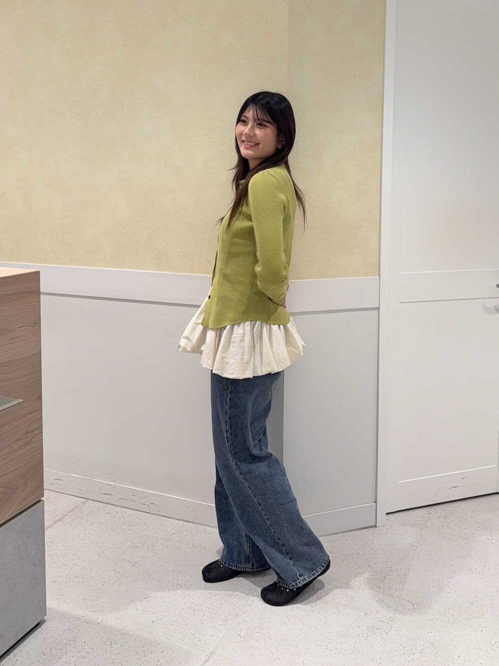 グリーン系のニット/セーター、ホワイト系のキャミソール、ブルー系のデニムパンツを着用したレディースの秋コーディネートの3枚目の写真