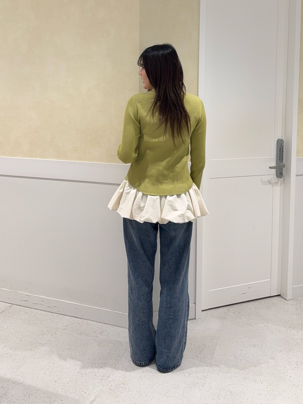 グリーン系のニット/セーター、ホワイト系のキャミソール、ブルー系のデニムパンツを着用したレディースの秋コーディネートの5枚目の写真