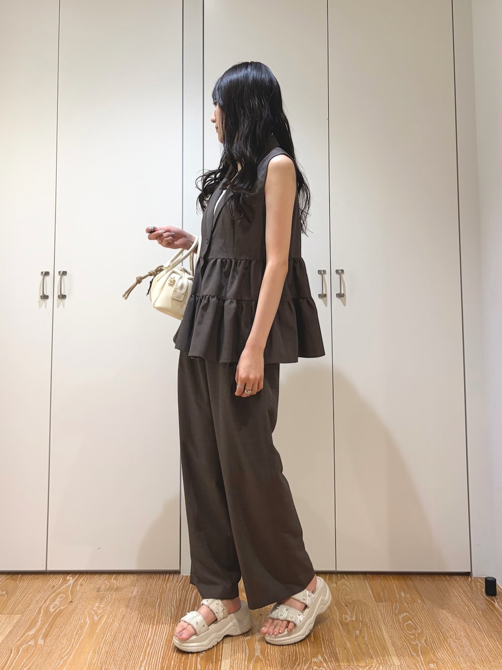 ブラウン系のベスト、ブラウン系のその他パンツ、ホワイト系のボストンバッグを着用したレディースの夏コーディネートの2枚目の写真