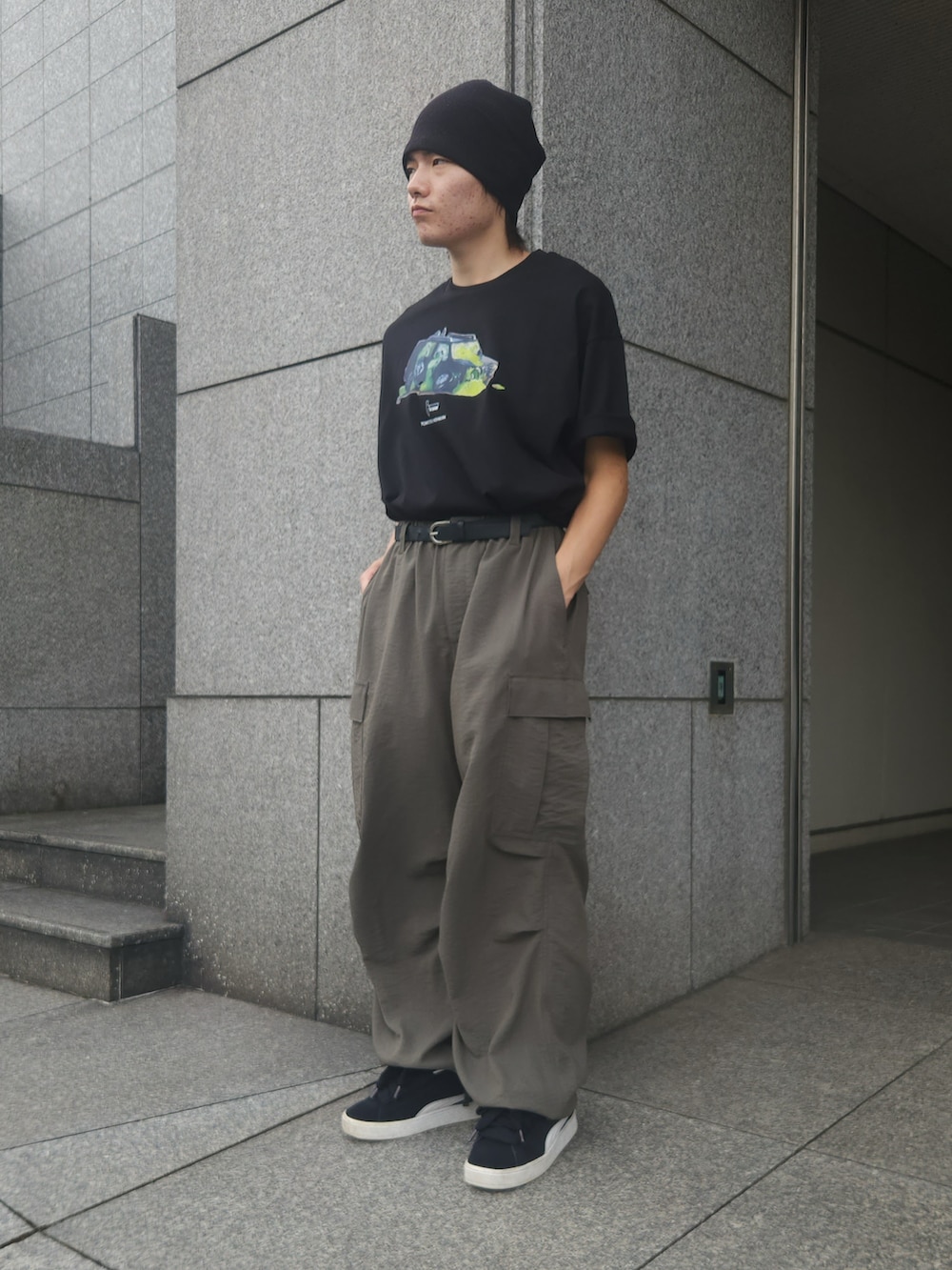 グリーン系のカーゴパンツ、ブラック系のTシャツ/カットソー、ブラック系のスニーカーを着用したメンズの夏コーディネートの2枚目の写真