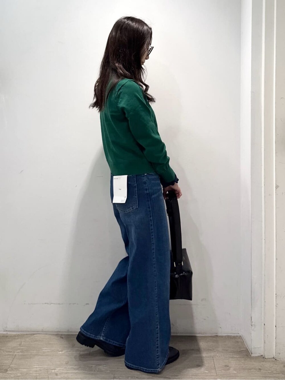 グリーン系のニット/セーター、ブルー系のデニムパンツ、ブラック系のショルダーバッグを着用したレディースの秋コーディネートの7枚目の写真