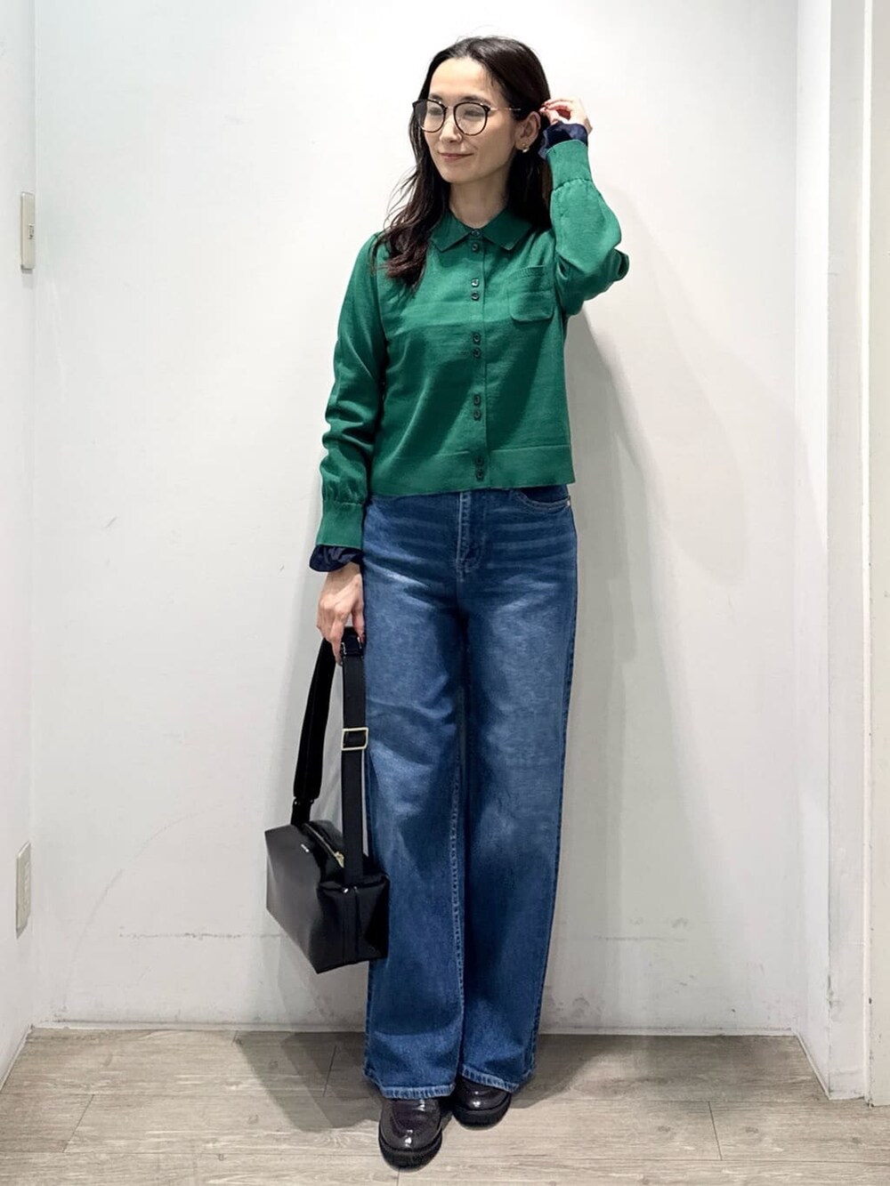 グリーン系のニット/セーター、ブルー系のデニムパンツ、ブラック系のショルダーバッグを着用したレディースの秋コーディネートの4枚目の写真