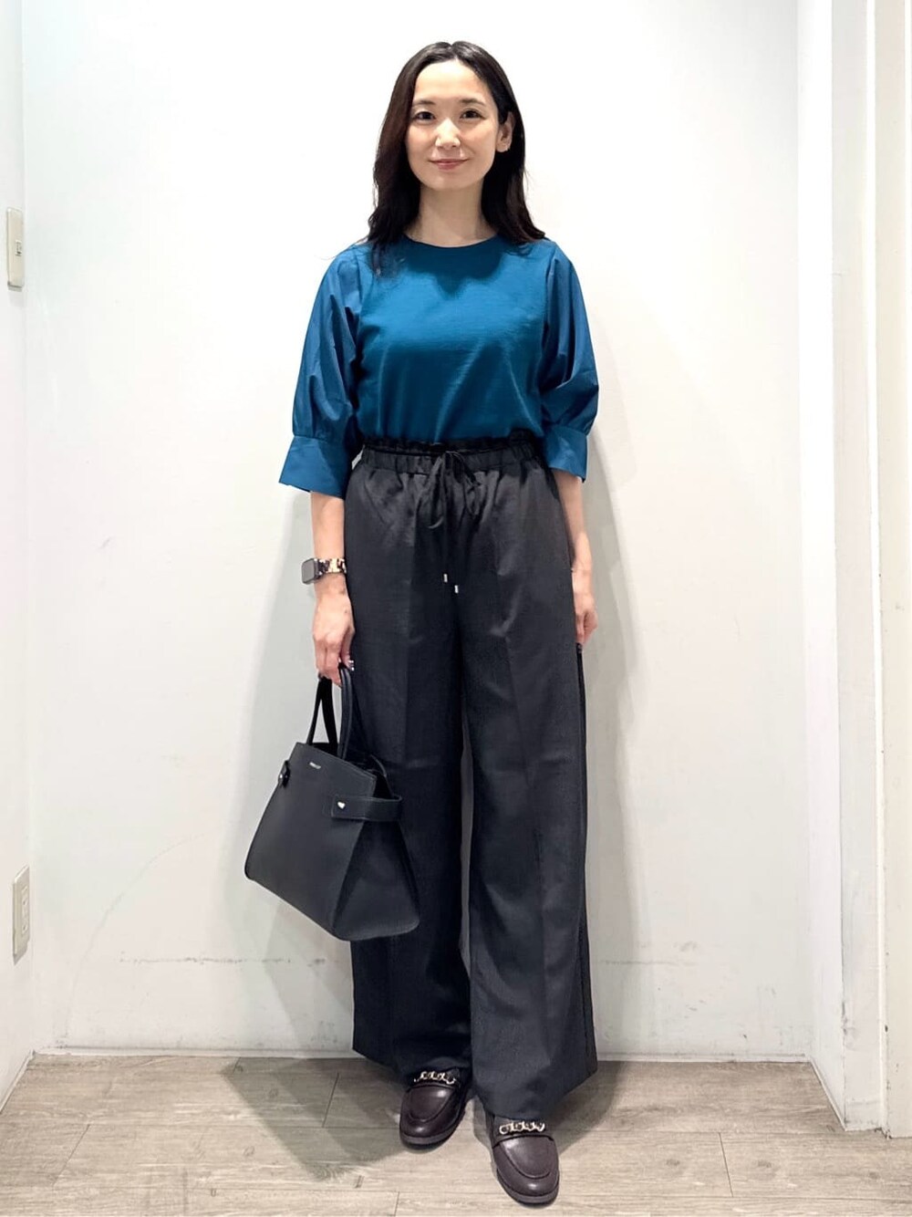 ブルー系のニット/セーター、グレー系のその他パンツ、ブラック系のショルダーバッグを着用したレディースの秋コーディネートの5枚目の写真