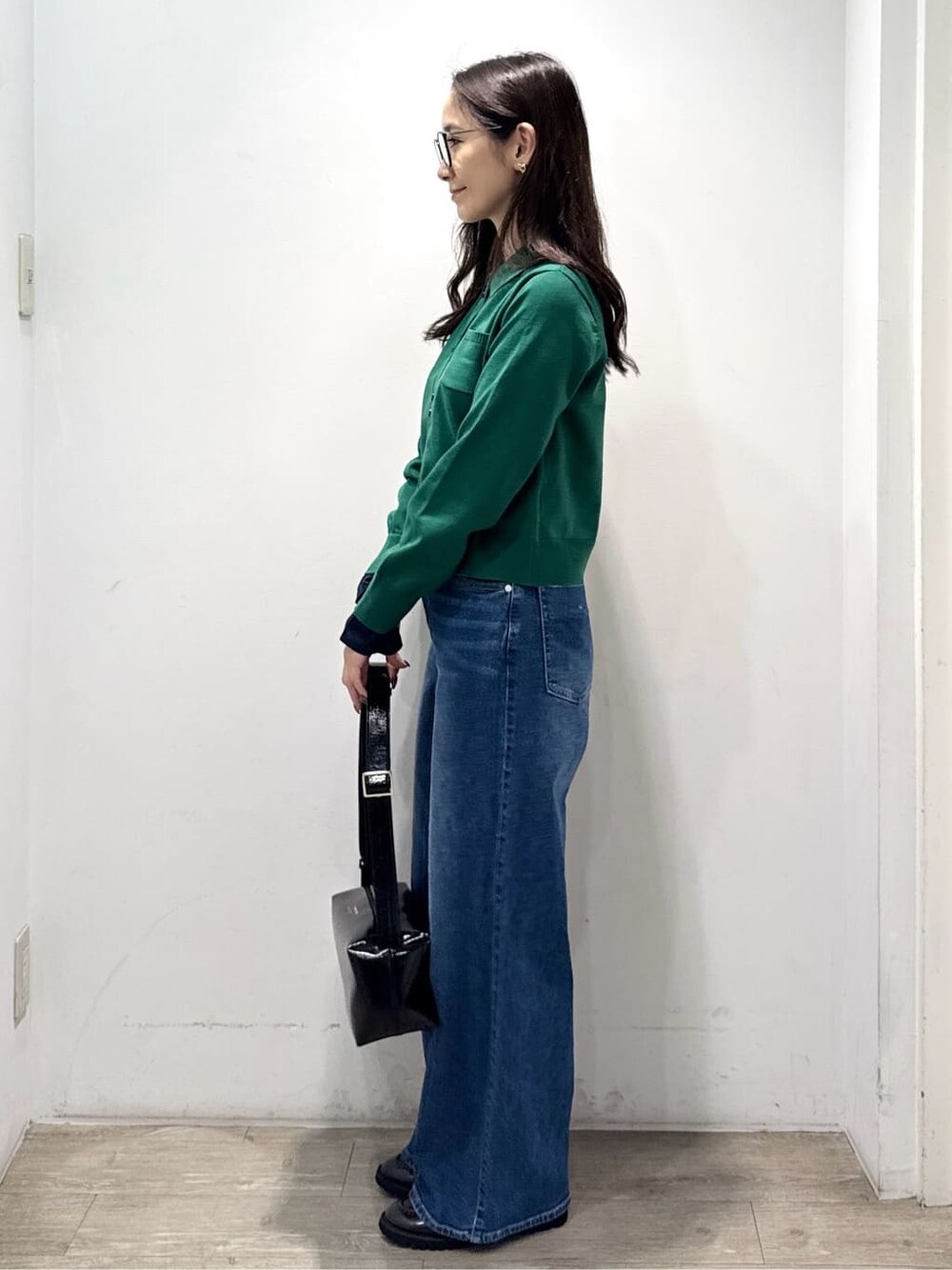 グリーン系のニット/セーター、ブルー系のデニムパンツ、ブラック系のショルダーバッグを着用したレディースの秋コーディネートの6枚目の写真