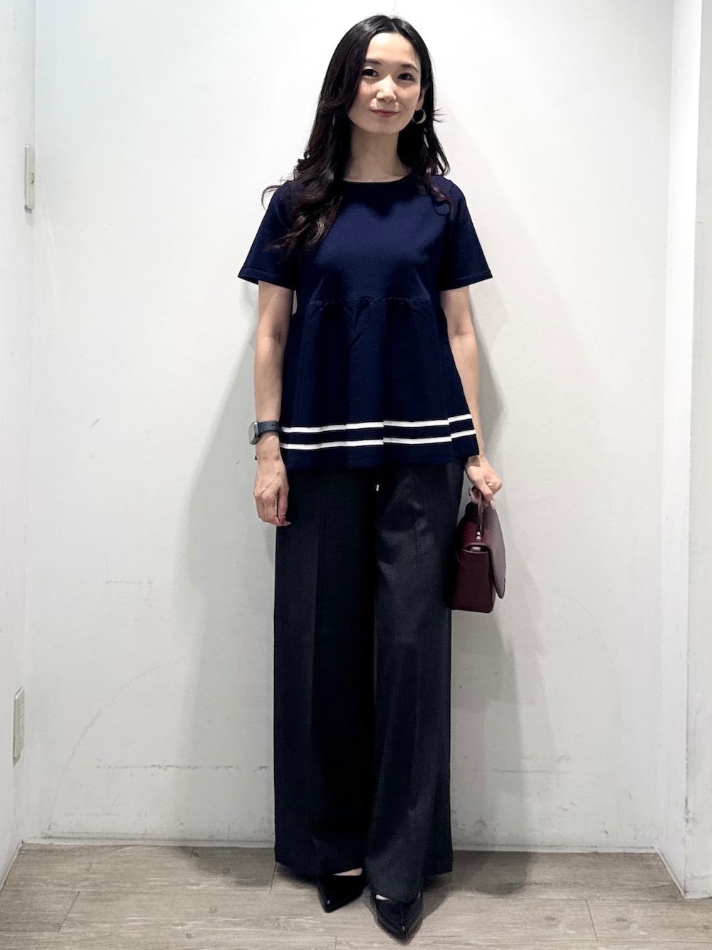 ブルー系のニット/セーター、グレー系のその他パンツ、レッド系のショルダーバッグを着用したレディースの夏コーディネートの5枚目の写真