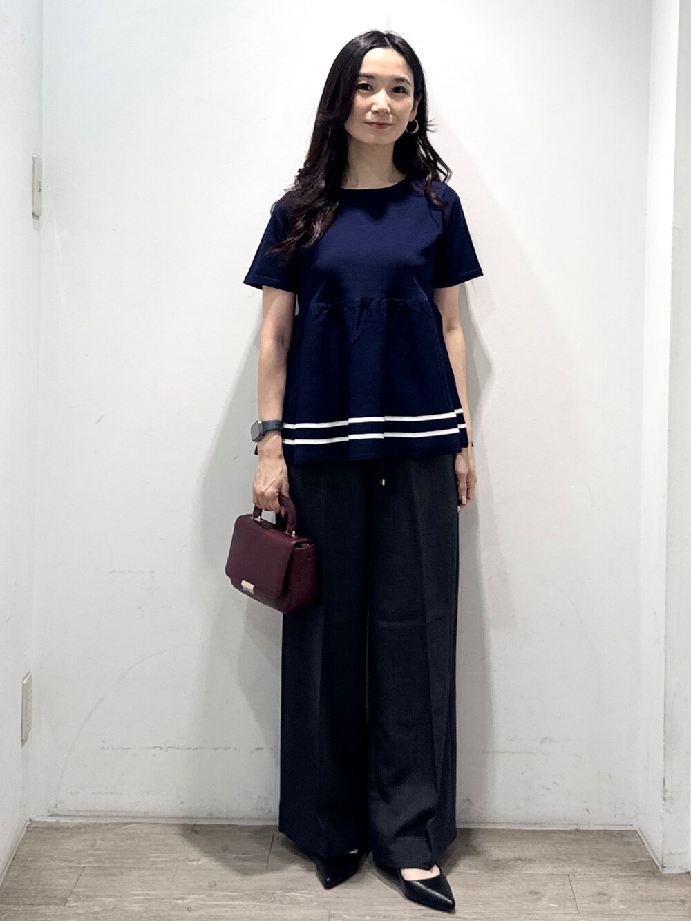 ブルー系のニット/セーター、グレー系のその他パンツ、レッド系のショルダーバッグを着用したレディースの夏コーディネートの6枚目の写真