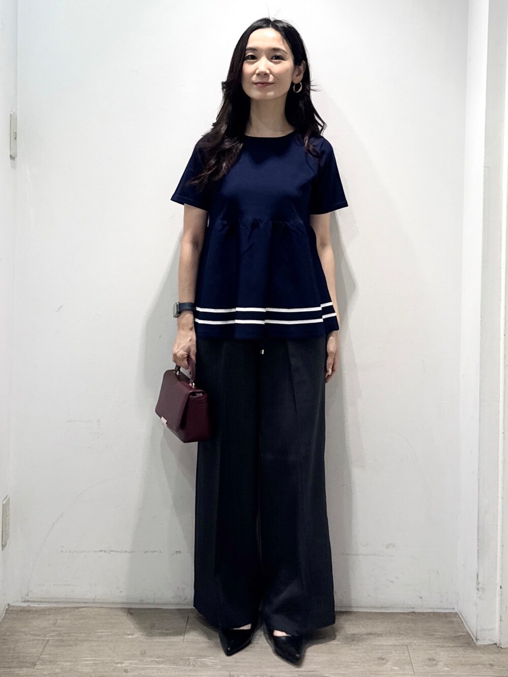 ブルー系のニット/セーター、グレー系のその他パンツ、レッド系のショルダーバッグを着用したレディースの夏コーディネートの3枚目の写真