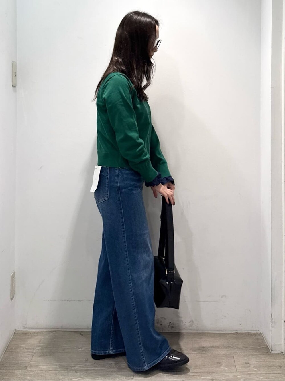 グリーン系のニット/セーター、ブルー系のデニムパンツ、ブラック系のショルダーバッグを着用したレディースの秋コーディネートの9枚目の写真
