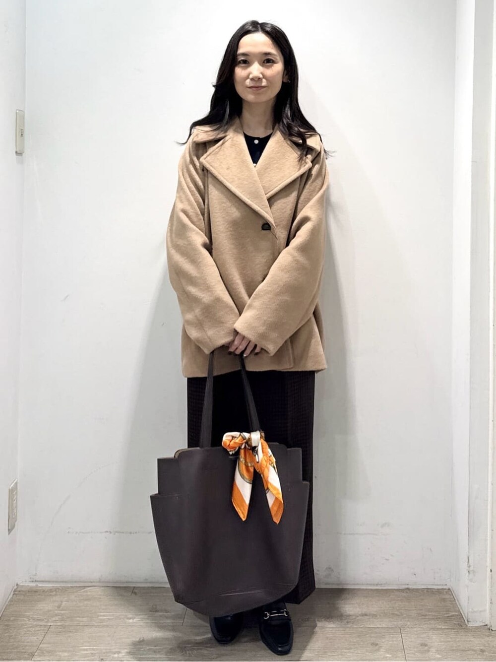 ベージュ系のピーコート、ブルー系のカーディガン/ボレロ、ブラウン系のその他パンツを着用したレディースの冬コーディネートの2枚目の写真